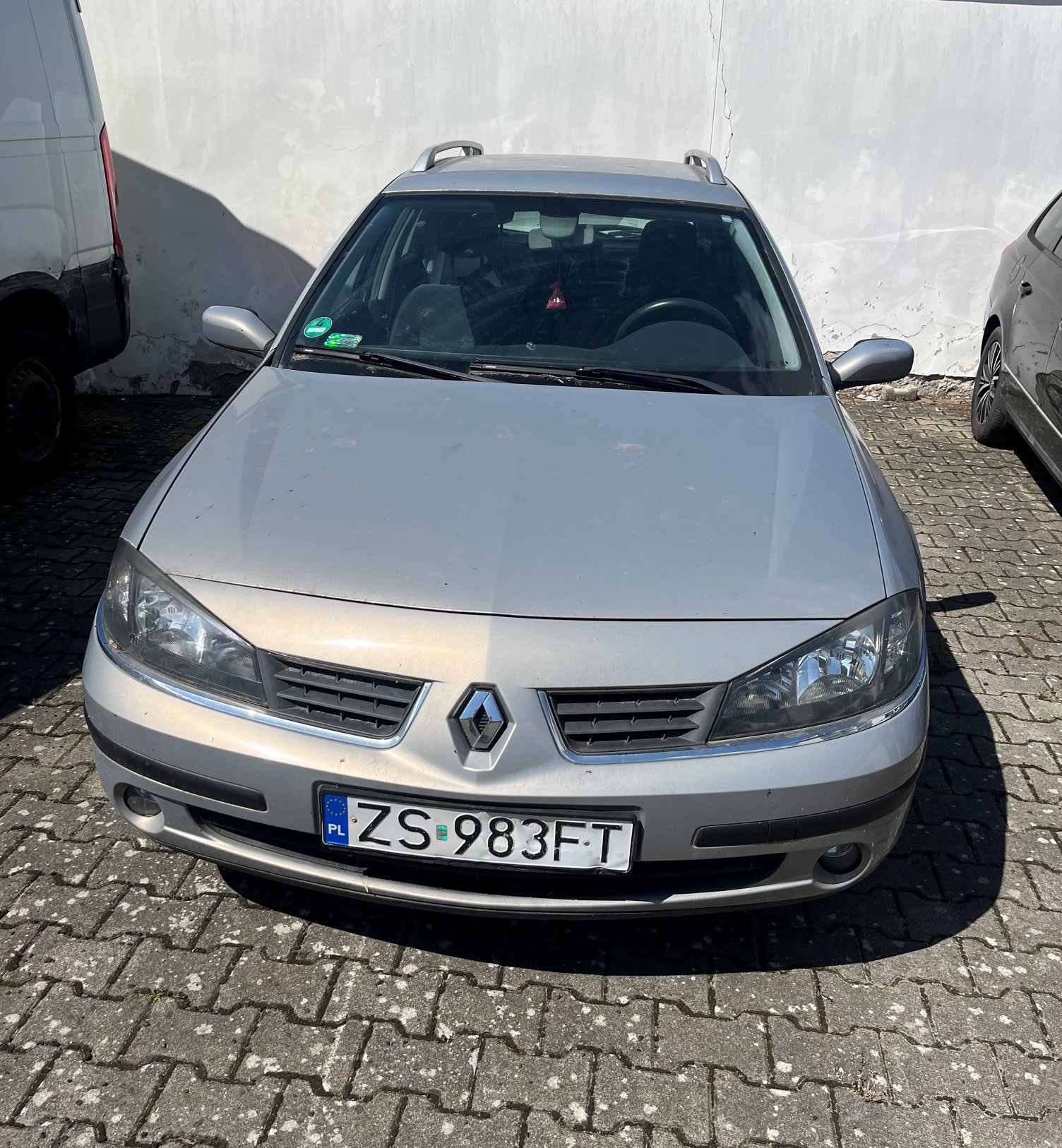 Przód srebrnego samochodu osobowego marki Renault Laguna z polską tablicą rejestracyjną o numerze ZS 983FT.