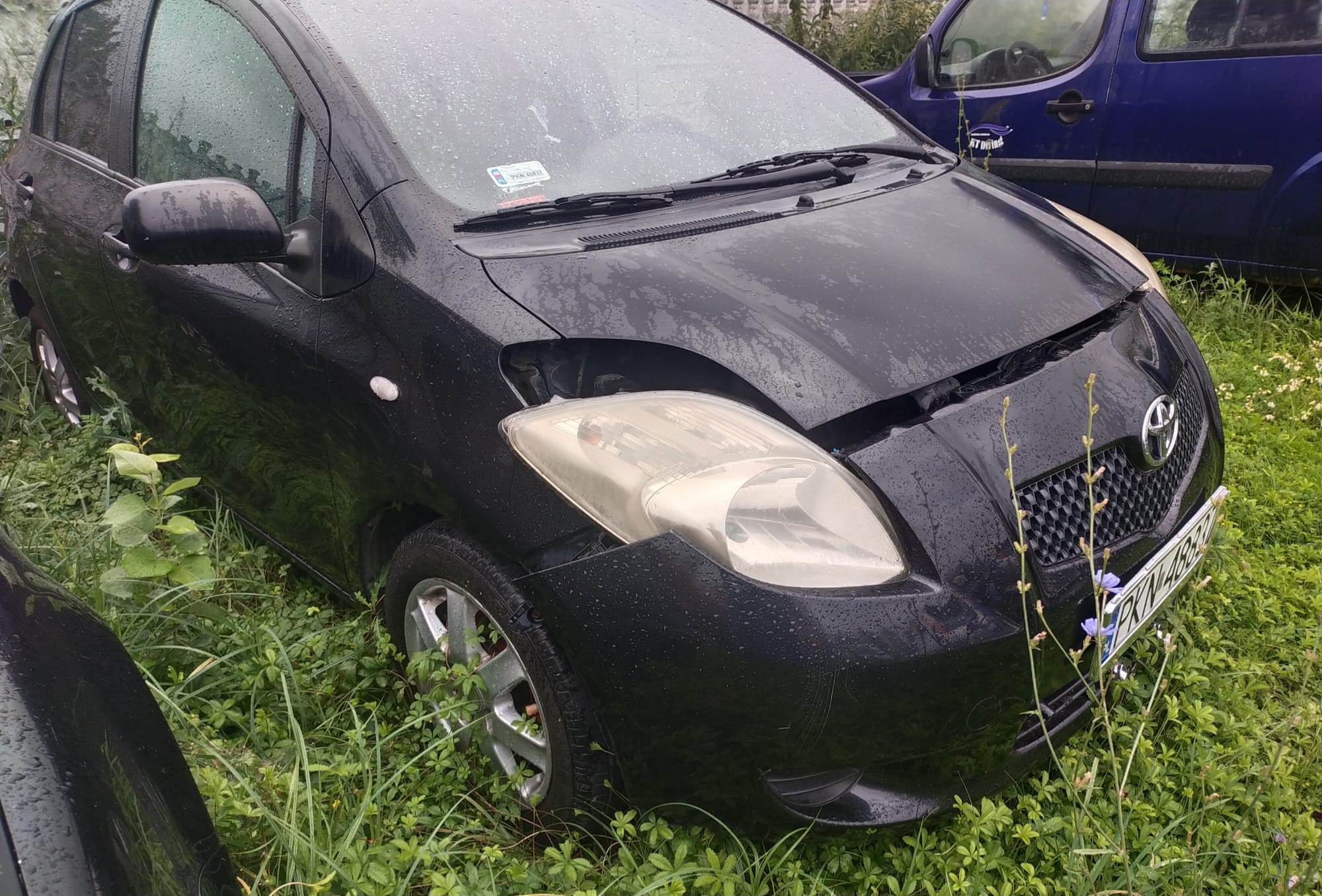 Czarna Toyota Yaris- pięciodrzwiowy samochód osobowy.