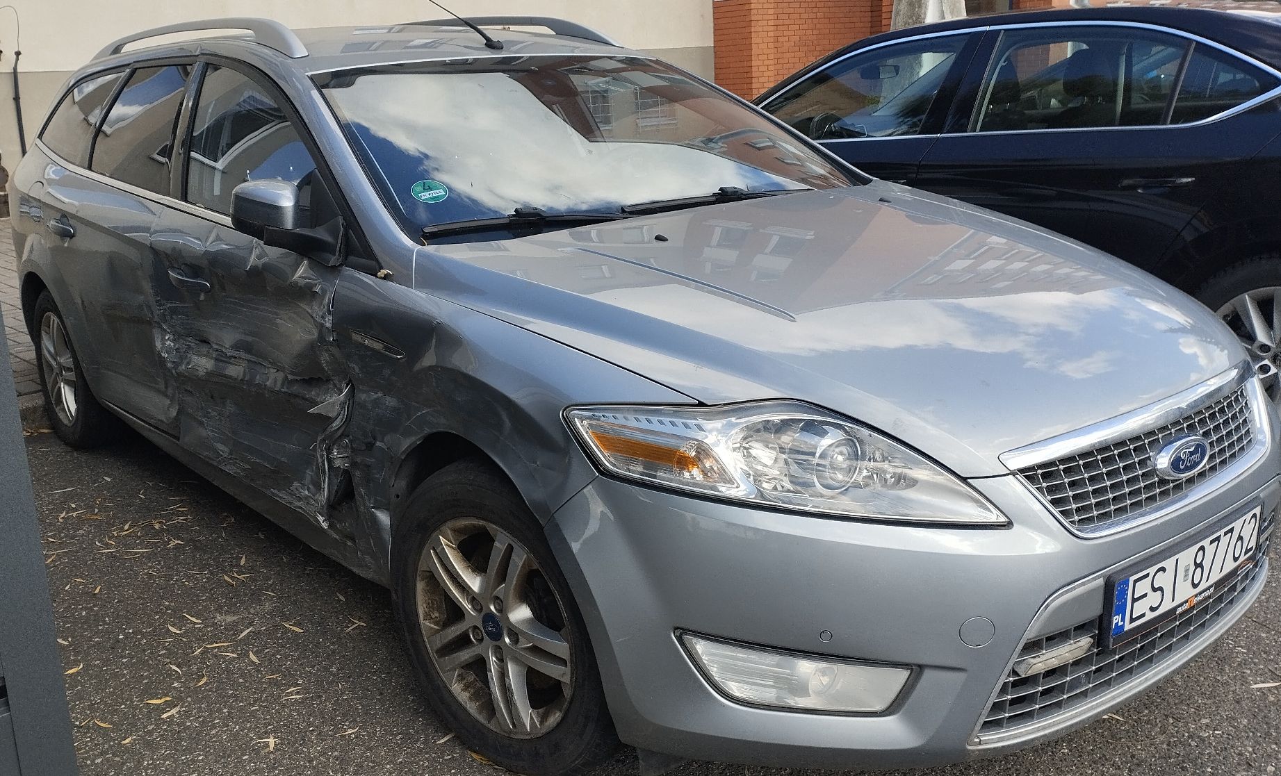 Przód srebrnego Forda Mondeo kombi z widocznym uszkodzonym prawym bokiem od strony pasażera.