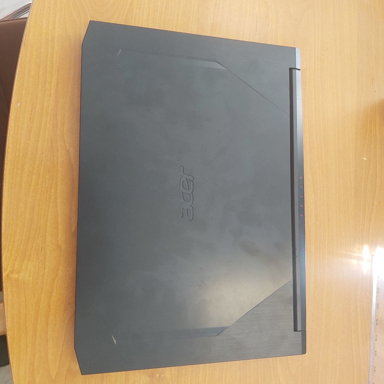 Góra laptopa z oznaczeniem marki, widoczne zarysowania.