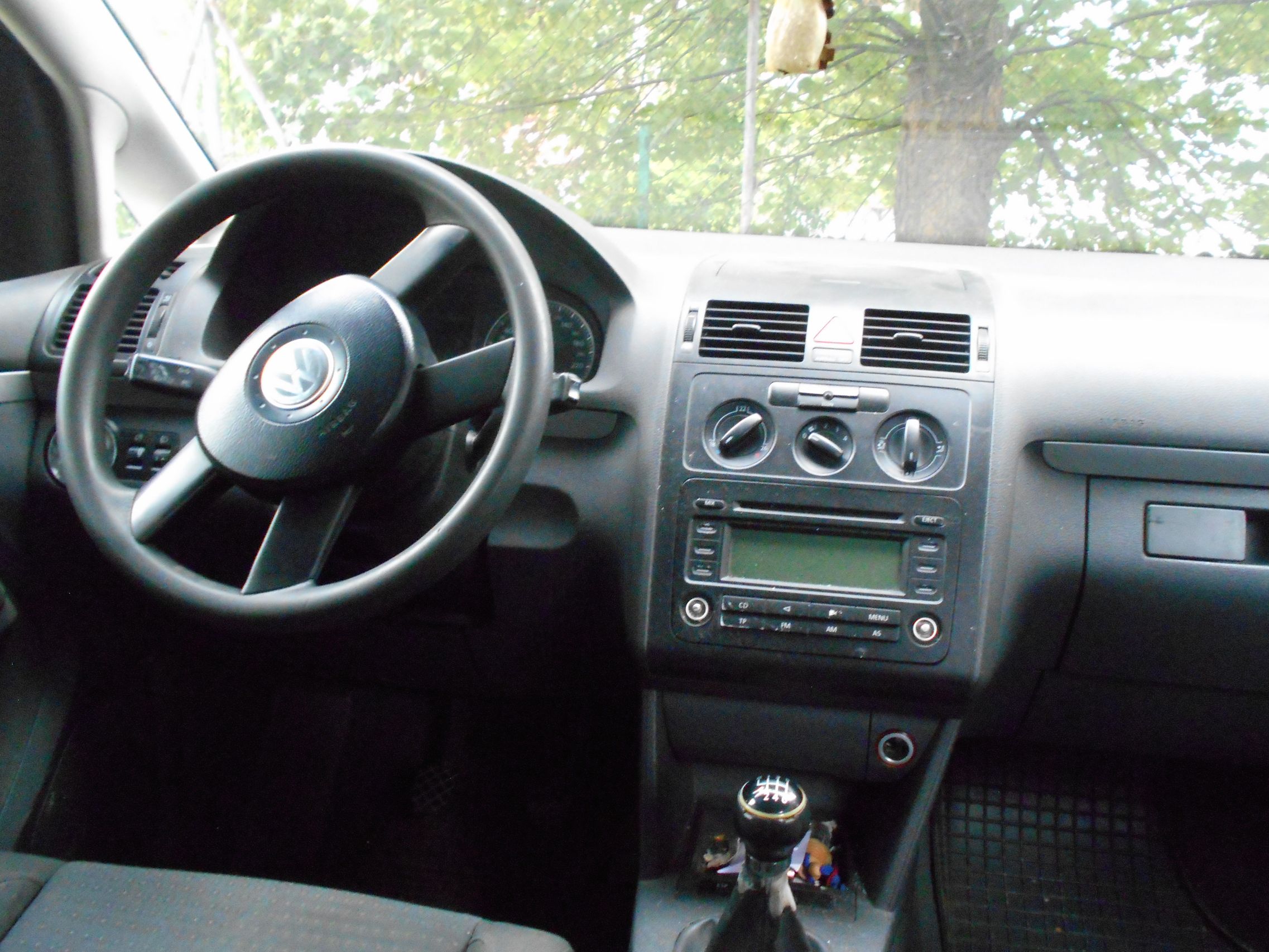Wnętrze samochodu z czarną kierownicą z logo Volkswagena