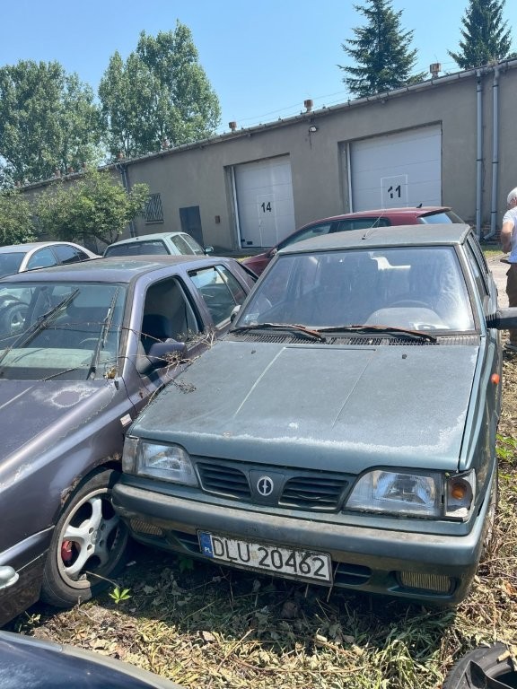 Maska pojazdu, lampa po stronie kierowcy rozbita, lakier zmatowiały, widoczne ślady korozji